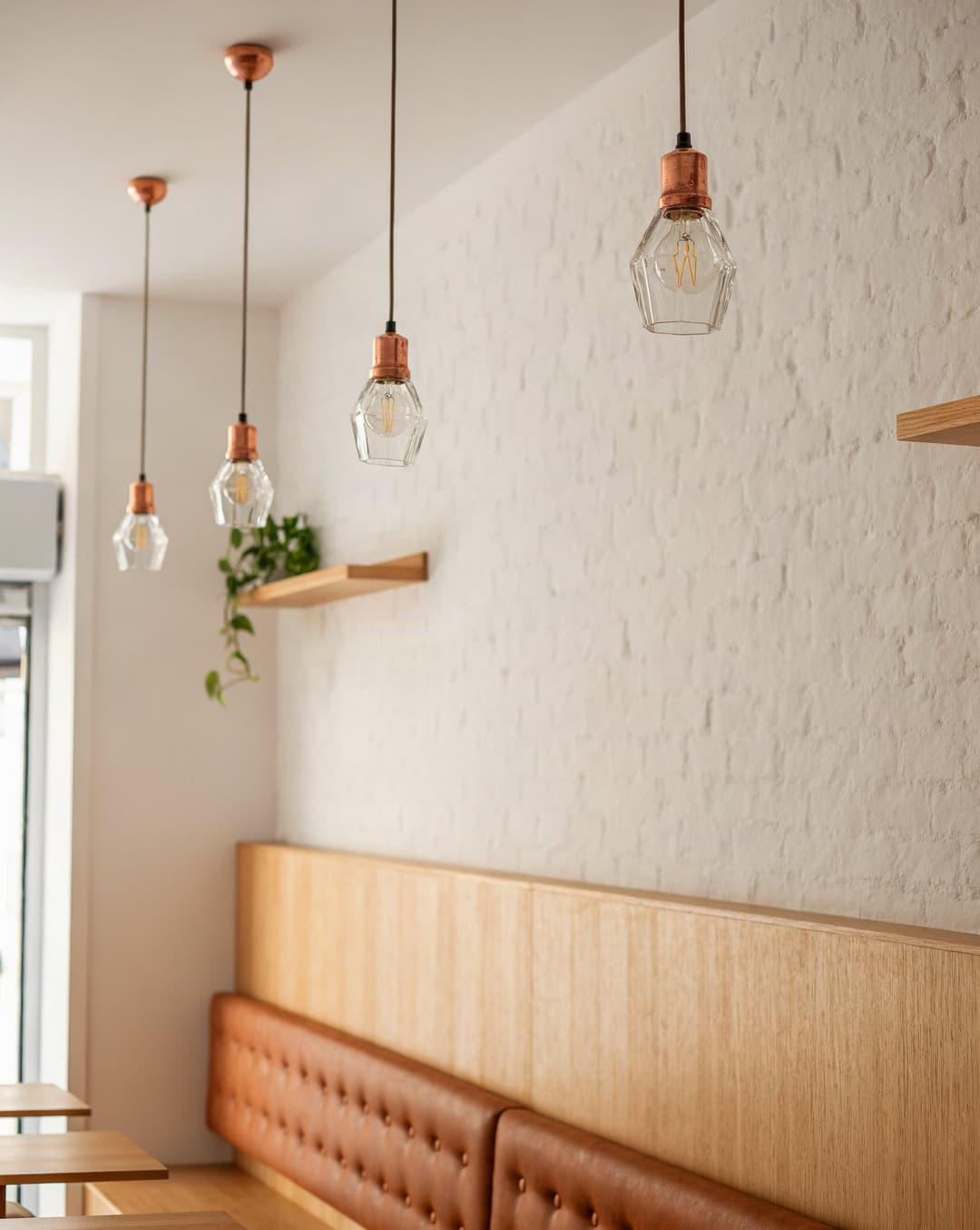 Filament pendants over the white wall and the leather banquette